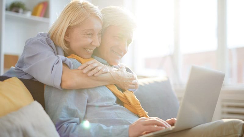 happy-senior-couple-using-laptop-in-sunlight-QZF346G(1)