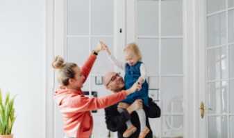 family playing and holding up daughter