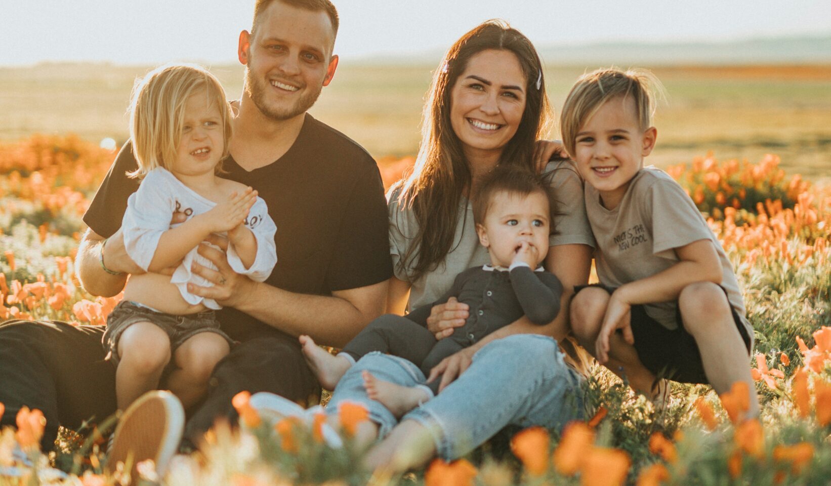 family sat in a field of flower smiling