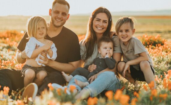 family sat in a field of flower smiling