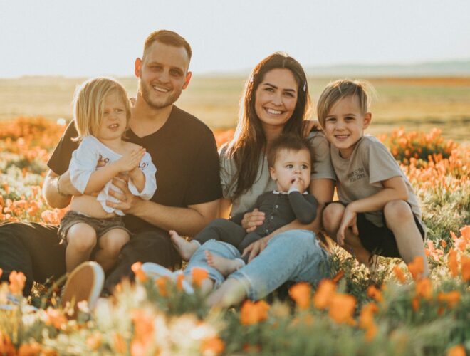 family sat in a field of flower smiling