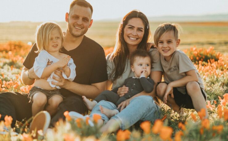 family sat in a field of flower smiling