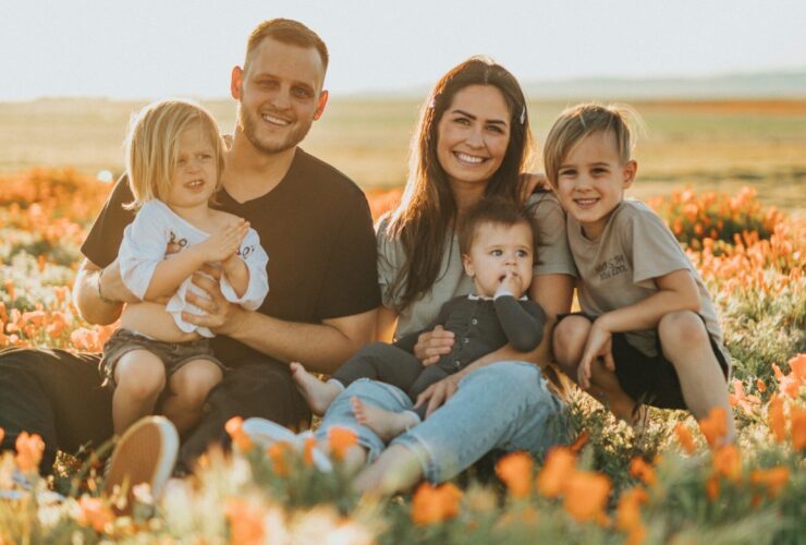 family sat in a field of flower smiling