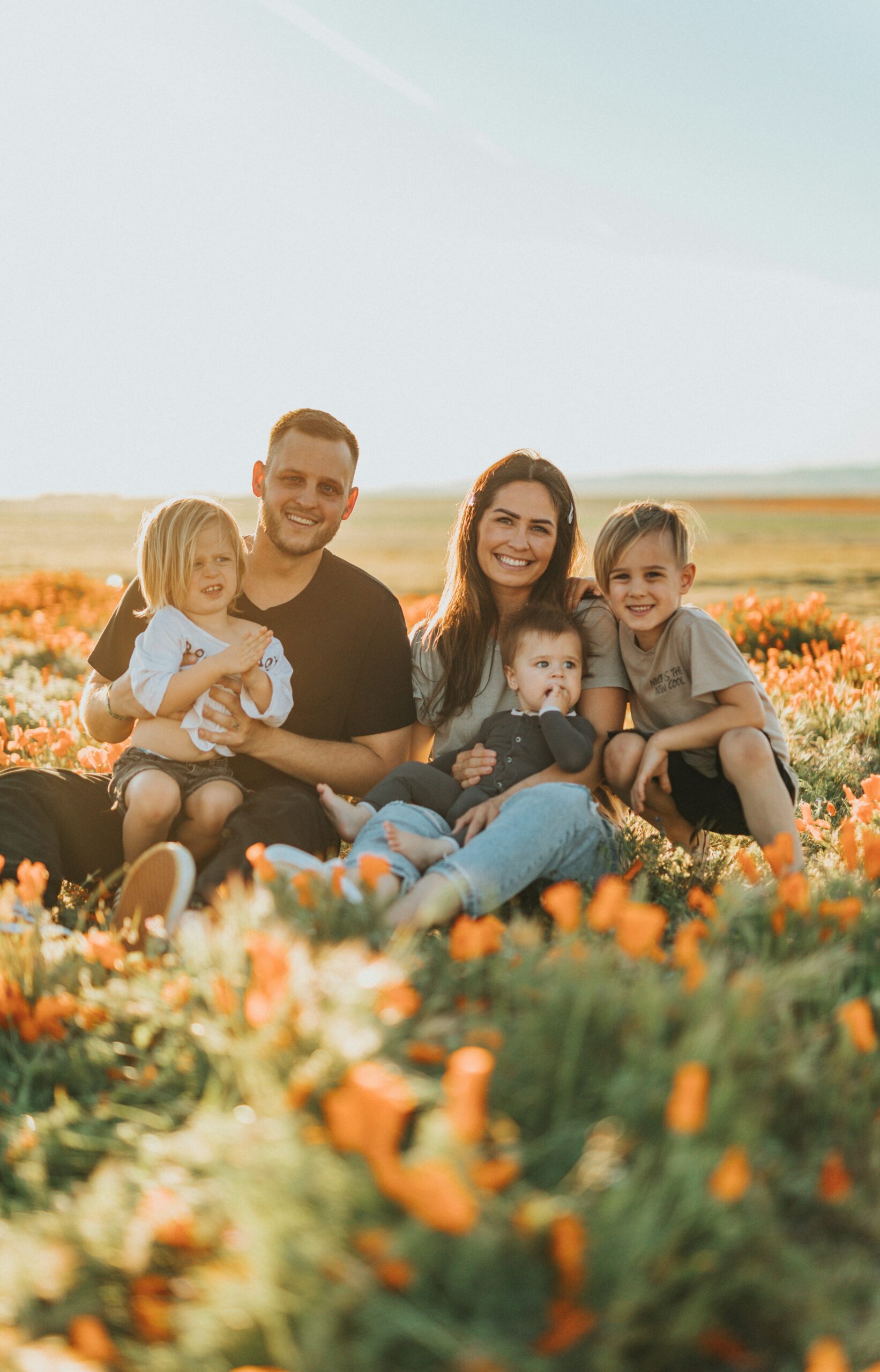 family sat in a field of flower smiling